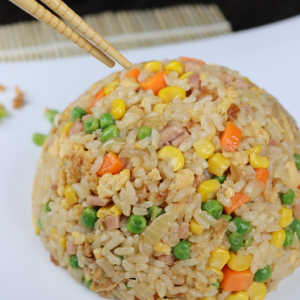 fried rice fried in a wok with diced ham, carrots, peas, onion, corn and fried onion