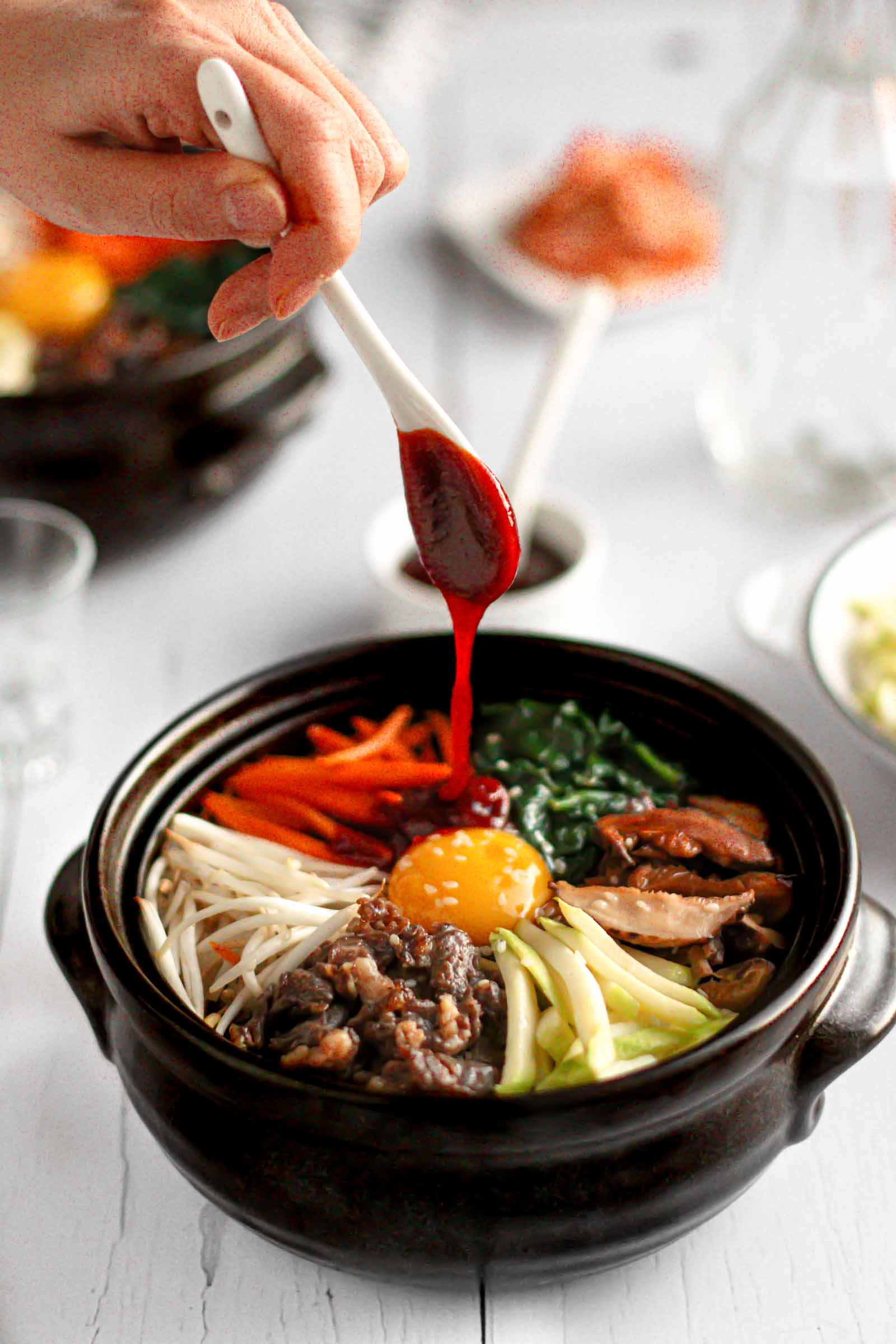 Dolsot bibimbap composed of rice, marinated beef, seasoned vegetables, one egg. sauce made out of gochujang.