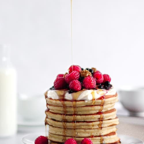 Pancakes thick and fluffy topped with fruits, yogurt and maple syrup.