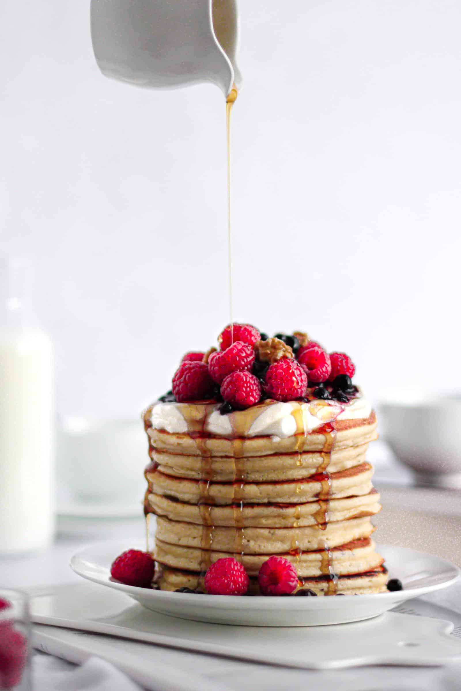 Pancakes thick and fluffy topped with fruits, yogurt and maple syrup