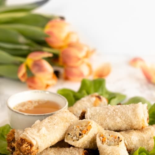 vietnamese nems fried spring rolls in a plate with flowers behing.