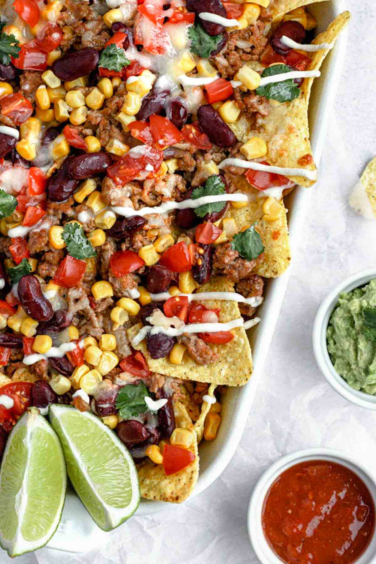 crispy tortilla chips, layer seasoned beef, juicy tomatoes, beans, corn, melted cheese and serve with some sour cream, spicy salsa sauce, and a creamy guacamole