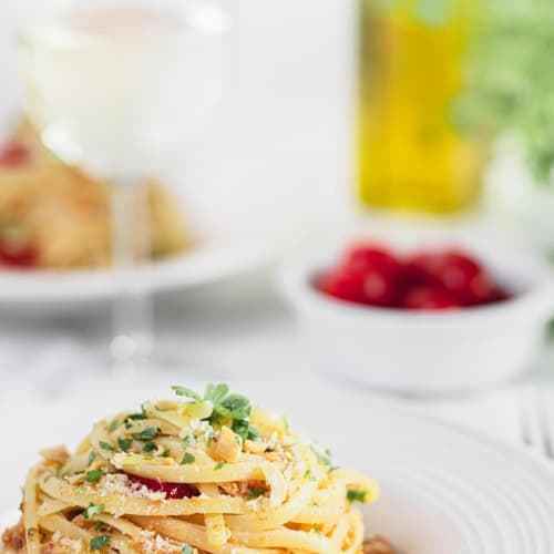 linguine pasta with sardines, tomatoes, peanuts, bread crumbs and parsley in a plate.