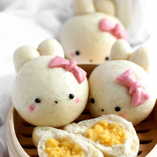 steamed buns in the shape of bunnies sitting in a steam basket.