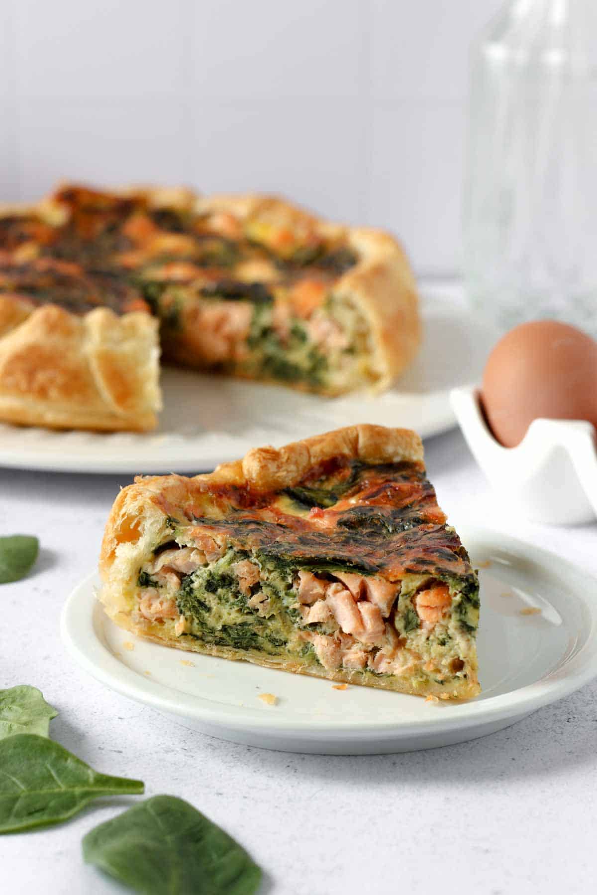 a slice of salmon and spinach quiche on a plate