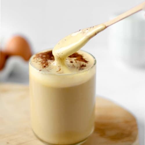 Vietnamese egg coffee in a cup with a spoon showing the creamy layer.