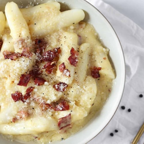 tteokbokki with carbonara sauce and bacon in a plate.