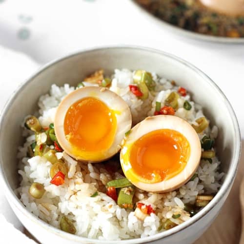 mayak eggs or korean marinated eggs in a bowl on top of steamed rice.