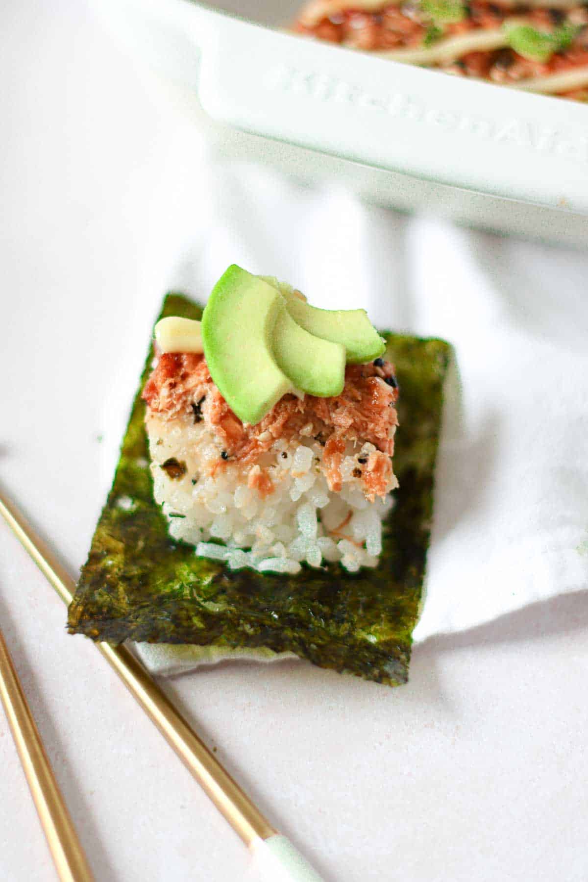a piece of salmon sushi bake accompanied with a roasted seaweed