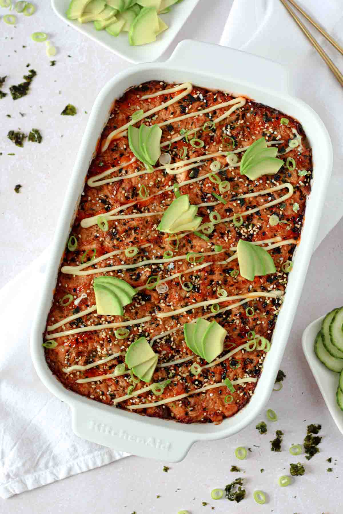 salmon sushi bake in a dish, topped with avocado slices