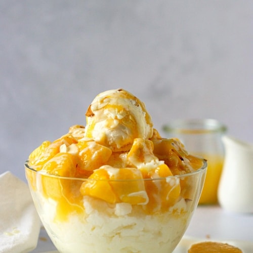 mango bingsu in a bowl with a scoop of ice cream and mango puree.