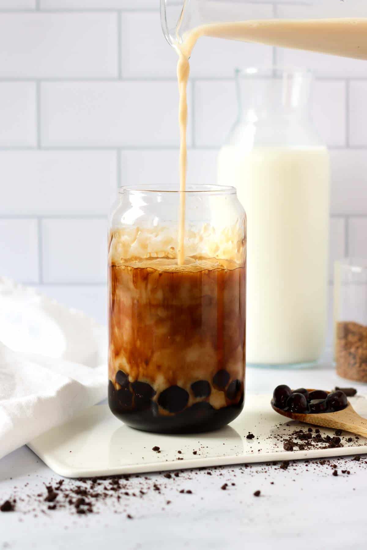 pouring tea into a glass with boba