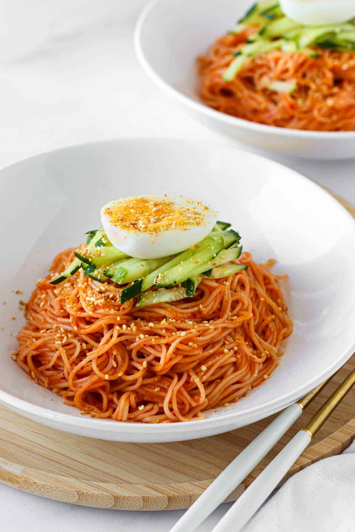 Bibim guksu spicy cold noodles topped with cucumber and boiled egg.
