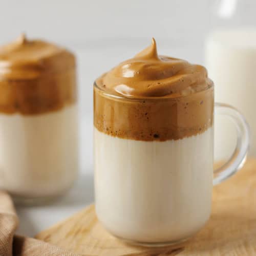 Dalgona coffee with whipped coffee foam over cold milk in a glass.
