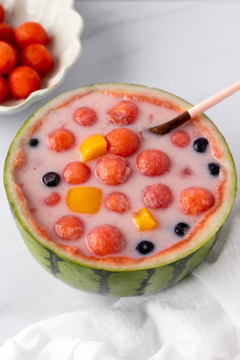watermelon hwachae featuring watermelon balls, canned peaches and blueberries.