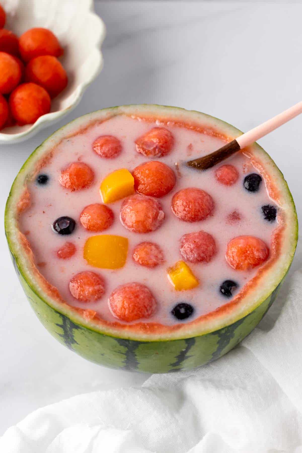 watermelon hwachae featuring watermelon balls, canned peaches and blueberries.