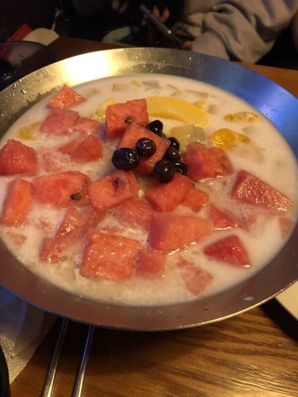 subak hwachae in a bowl with blueberries and peaches.